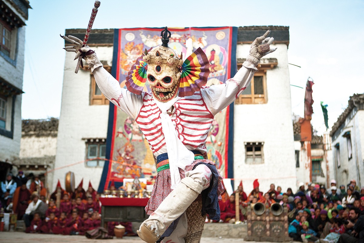 A masked dancer performs before a monastery during a festival in Upper Mustang